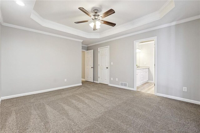 unfurnished bedroom with baseboards, visible vents, a raised ceiling, and light colored carpet