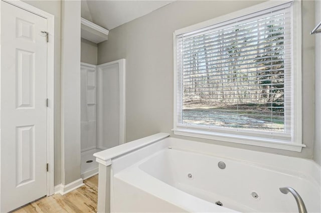 full bath featuring a tub with jets, plenty of natural light, and wood finished floors