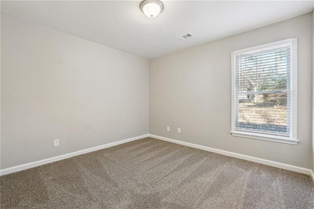 spare room with carpet, visible vents, and baseboards