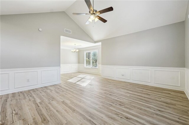 spare room with lofted ceiling, light wood-style flooring, ceiling fan, and wainscoting