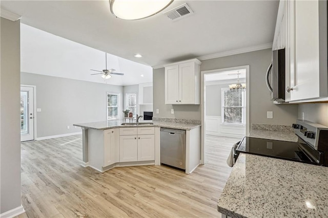 20 Trace Ct, Covington, GA 30016 - kitchen featuring stainless steel appliances, a peninsula, white cabinetry, light wood finished floors, and crown molding