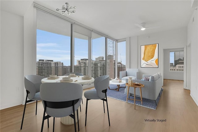 dining space featuring ceiling fan, a wall of windows, and light hardwood / wood-style floors