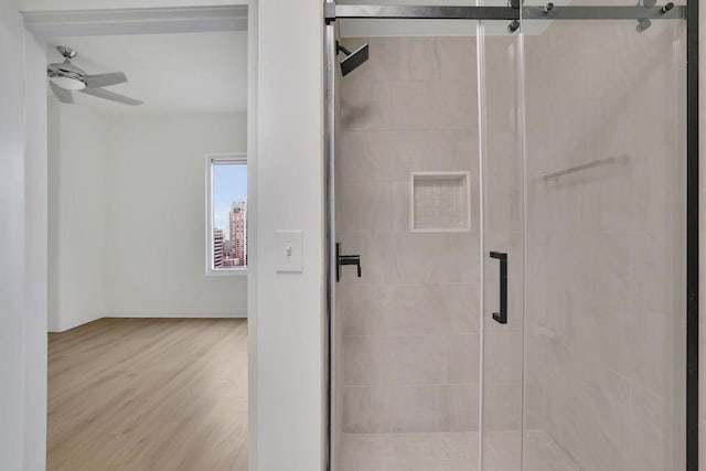 bathroom featuring ceiling fan, wood-type flooring, and a shower with door