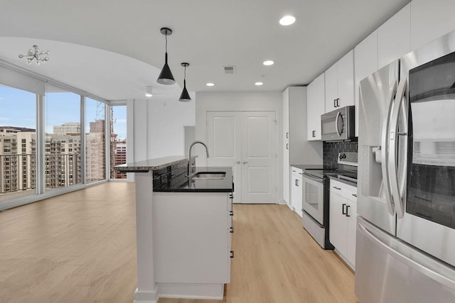 kitchen featuring sink, stainless steel appliances, tasteful backsplash, white cabinets, and decorative light fixtures