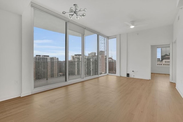 empty room with ceiling fan, a healthy amount of sunlight, and light wood-type flooring