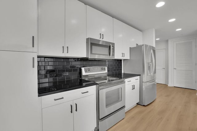 kitchen featuring backsplash, light hardwood / wood-style flooring, white cabinets, and appliances with stainless steel finishes