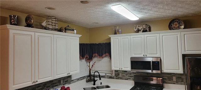 kitchen with white cabinetry, sink, tasteful backsplash, black fridge, and range