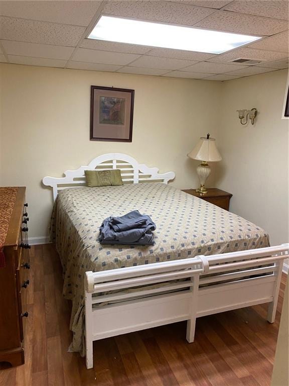 bedroom with a paneled ceiling and hardwood / wood-style flooring