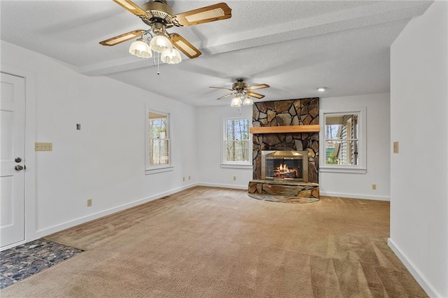 unfurnished living room featuring carpet, a textured ceiling, ceiling fan, beamed ceiling, and a fireplace