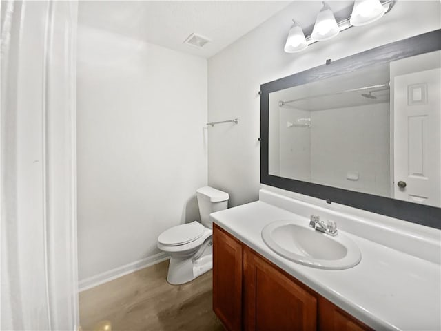 bathroom featuring toilet, wood finished floors, visible vents, vanity, and baseboards