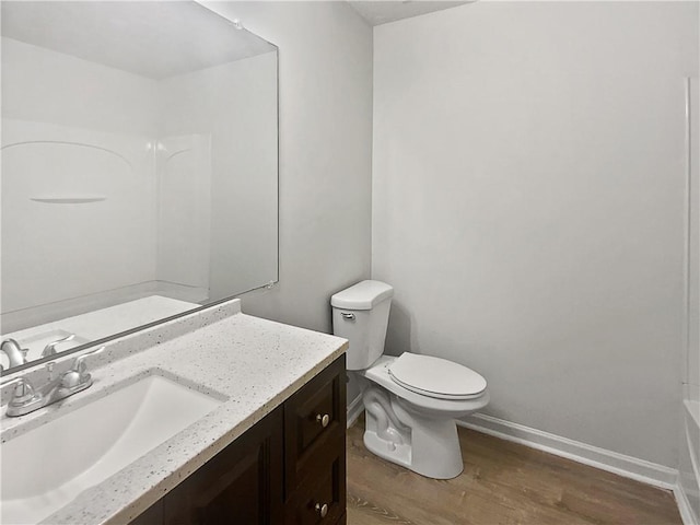 bathroom with wood finished floors, vanity, toilet, and baseboards