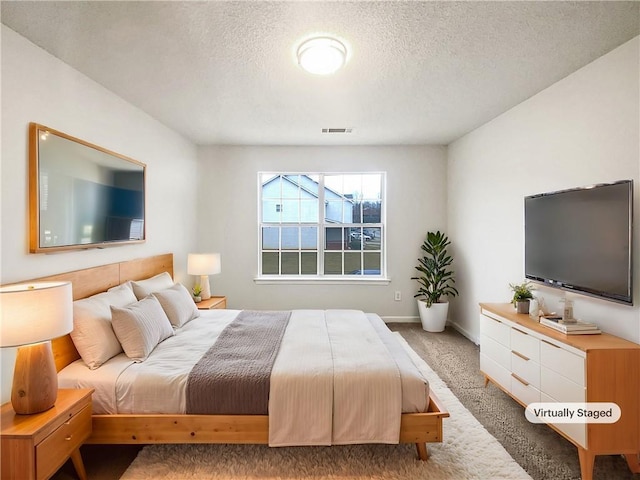 carpeted bedroom with visible vents, a textured ceiling, and baseboards