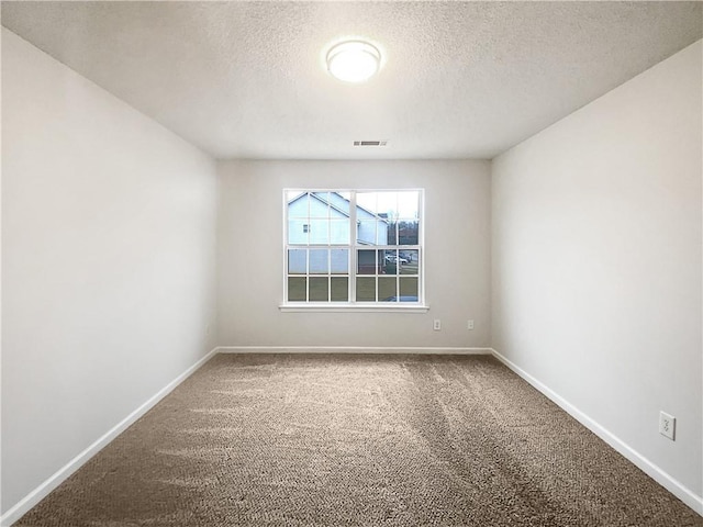 carpeted spare room featuring visible vents, a textured ceiling, and baseboards