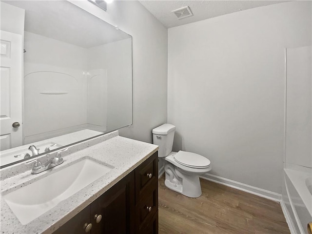 full bathroom with visible vents, toilet, wood finished floors, a washtub, and vanity