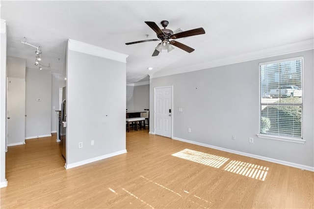 empty room featuring light wood-style flooring, crown molding, baseboards, and a ceiling fan