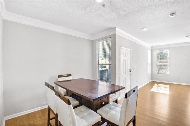 dining room with light wood-type flooring, plenty of natural light, and ornamental molding