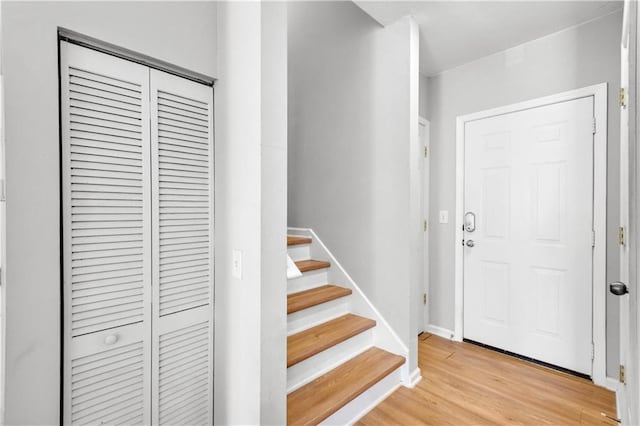 entryway with baseboards, stairway, and light wood finished floors