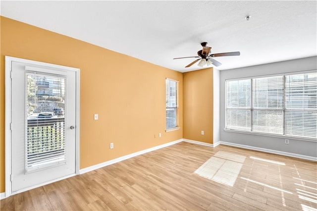 spare room with light wood-type flooring, plenty of natural light, and baseboards