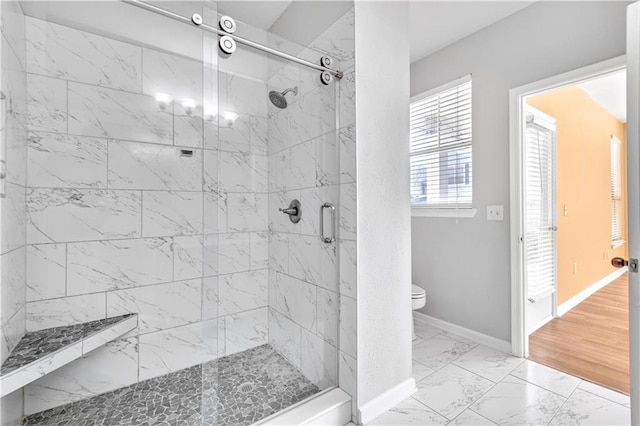 full bathroom featuring toilet, marble finish floor, a marble finish shower, and baseboards