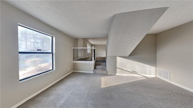 spare room with a textured ceiling and carpet flooring