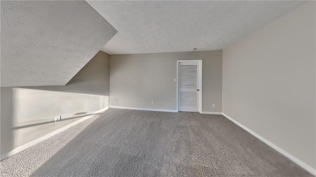 additional living space with carpet flooring and a textured ceiling