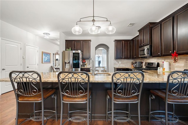 kitchen with arched walkways, visible vents, dark brown cabinets, and appliances with stainless steel finishes