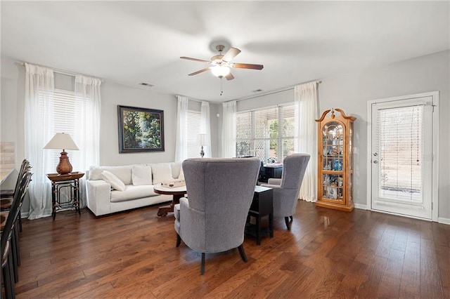 living room with visible vents, baseboards, ceiling fan, and dark wood-style flooring