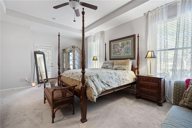 bedroom with a ceiling fan, a raised ceiling, light colored carpet, and baseboards