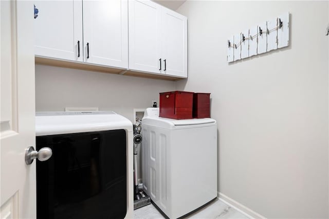 clothes washing area featuring washing machine and dryer, cabinet space, and baseboards