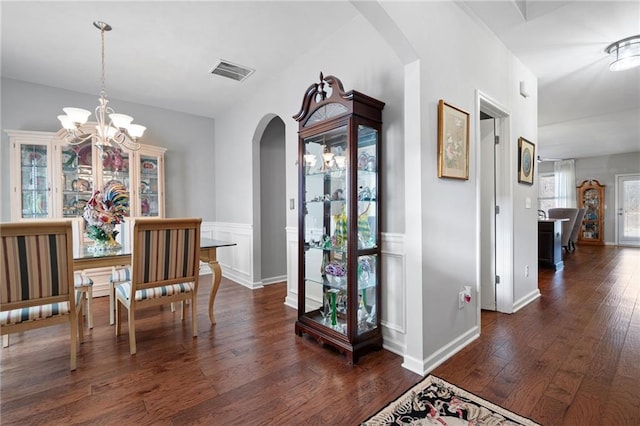 interior space featuring visible vents, baseboards, arched walkways, dark wood-style floors, and a notable chandelier