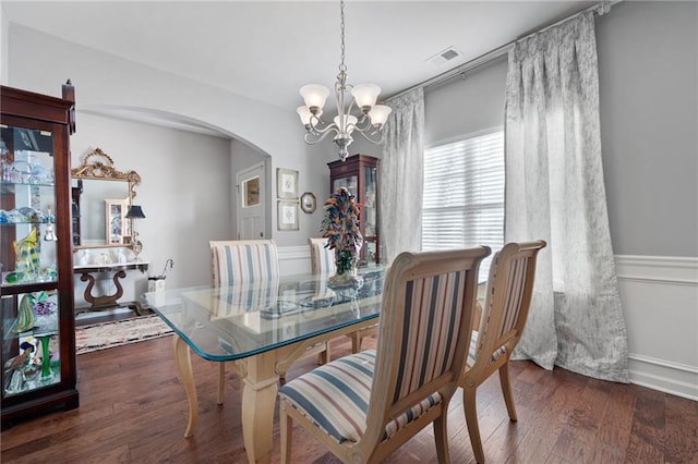 dining room featuring visible vents, arched walkways, wood finished floors, and a chandelier