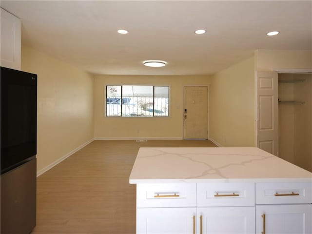 kitchen with refrigerator, white cabinetry, and recessed lighting