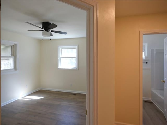 interior space with ceiling fan, dark wood finished floors, visible vents, and baseboards