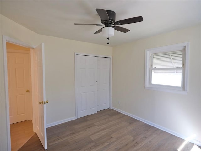 unfurnished bedroom featuring ceiling fan, a closet, wood finished floors, and baseboards
