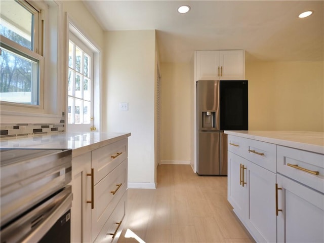kitchen featuring stainless steel fridge, white cabinets, light countertops, backsplash, and recessed lighting