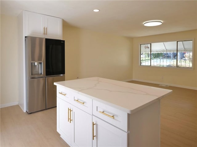 kitchen with light stone countertops, a center island, light wood finished floors, and stainless steel fridge with ice dispenser