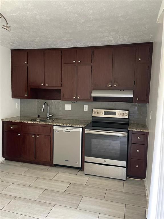 kitchen featuring tasteful backsplash, light stone countertops, sink, and stainless steel appliances