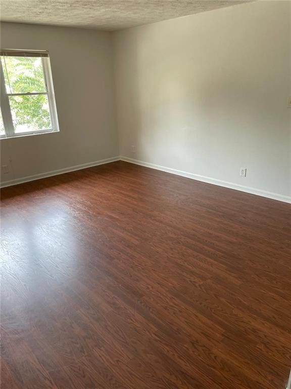 empty room featuring dark hardwood / wood-style floors and a textured ceiling