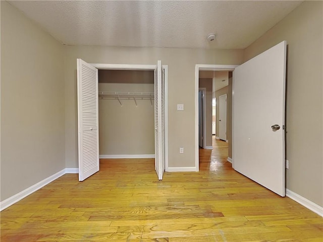 unfurnished bedroom with a textured ceiling, light hardwood / wood-style floors, and a closet