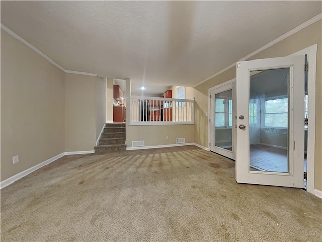 unfurnished living room with crown molding, carpet floors, a textured ceiling, and french doors