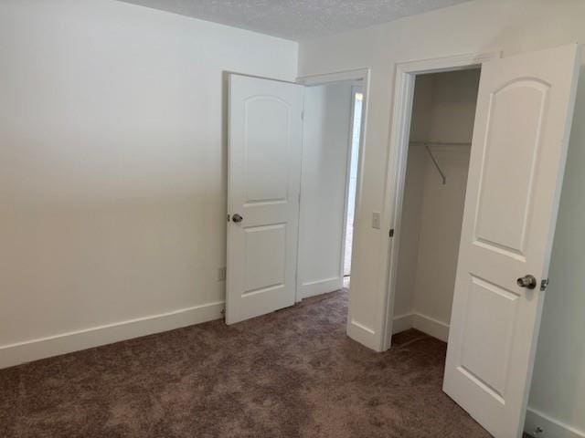 712 Emily St SE, Gainesville, GA 30501 - unfurnished bedroom with dark colored carpet, a closet, baseboards, and a textured ceiling