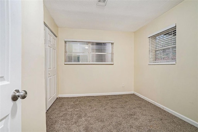 carpeted spare room featuring a textured ceiling