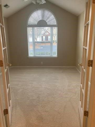 spare room with vaulted ceiling and light colored carpet