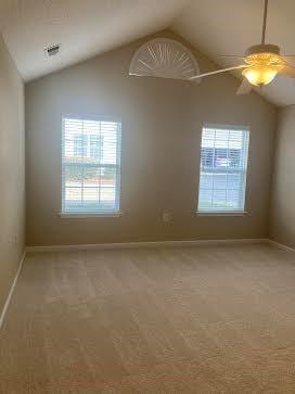 carpeted empty room with vaulted ceiling, plenty of natural light, and ceiling fan