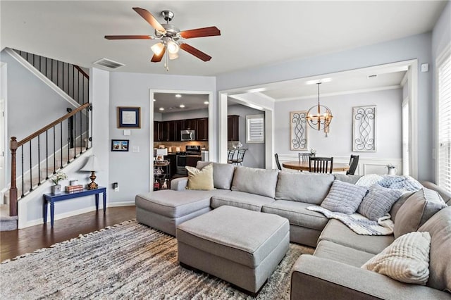 living area with wood finished floors, stairs, visible vents, and ceiling fan with notable chandelier