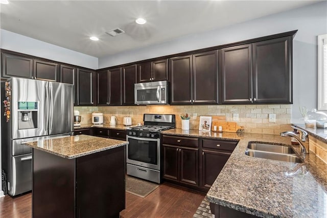 kitchen featuring a sink, stone countertops, visible vents, appliances with stainless steel finishes, and dark wood-style floors