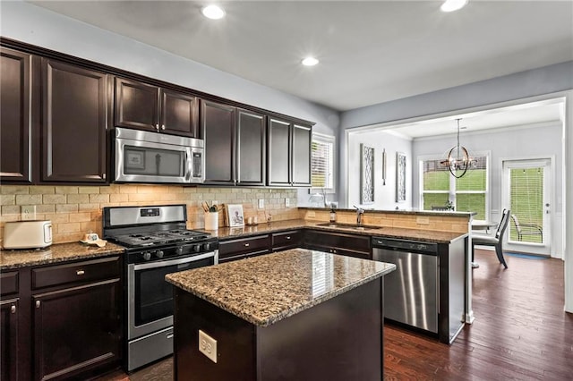 kitchen featuring dark brown cabinets, a sink, decorative backsplash, stone countertops, and appliances with stainless steel finishes
