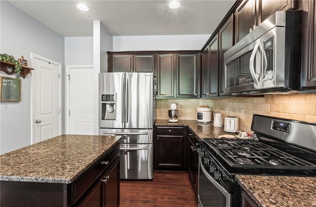 kitchen featuring stainless steel appliances, dark wood-type flooring, dark brown cabinetry, and dark stone countertops