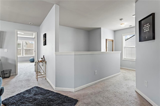hallway with plenty of natural light, baseboards, and carpet