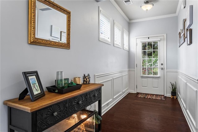 doorway featuring dark wood finished floors, a decorative wall, ornamental molding, and visible vents